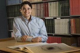 Joshua Sokol sitting at a desk in a library